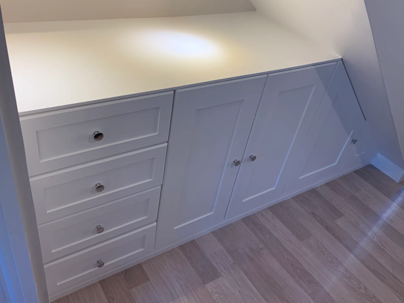 A fitted understairs draw and cupboard unit finished in brilliant white paint