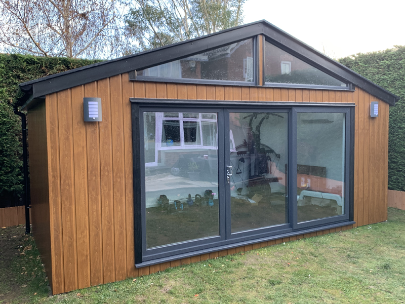 Front view of completed structure with UPVC cladding, sliding patio doors and triangular windows