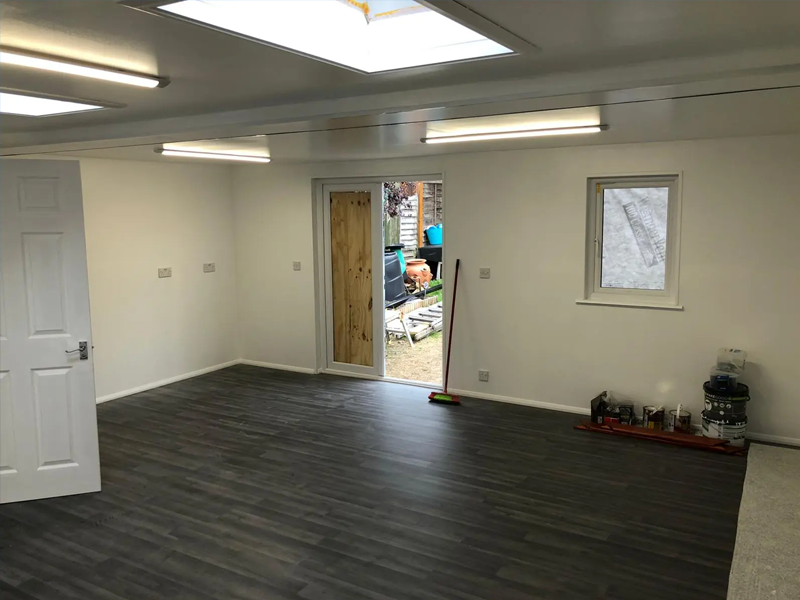 The internal view of a large garden room with skylights, strip lighting and laminate flooring