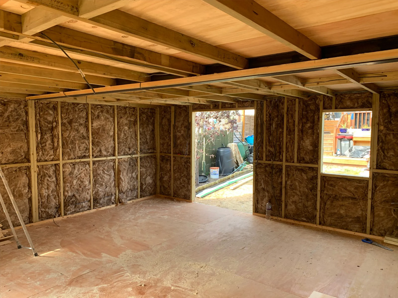 insulated internal walls and ceiling view , treated timber stud walls , roof joists and openings for doors and windows 